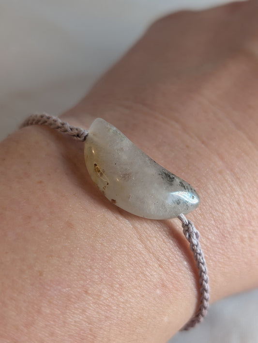 Bracelet with a stone bead on a wrist against a neutral background
