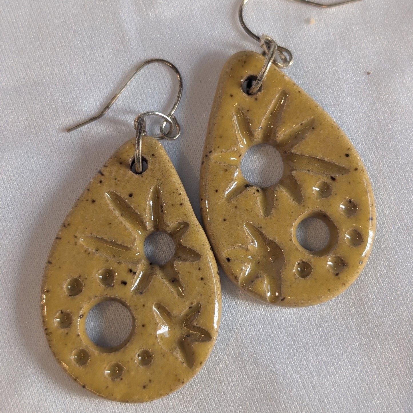 Pair of yellow ceramic earrings with star designs on a white background