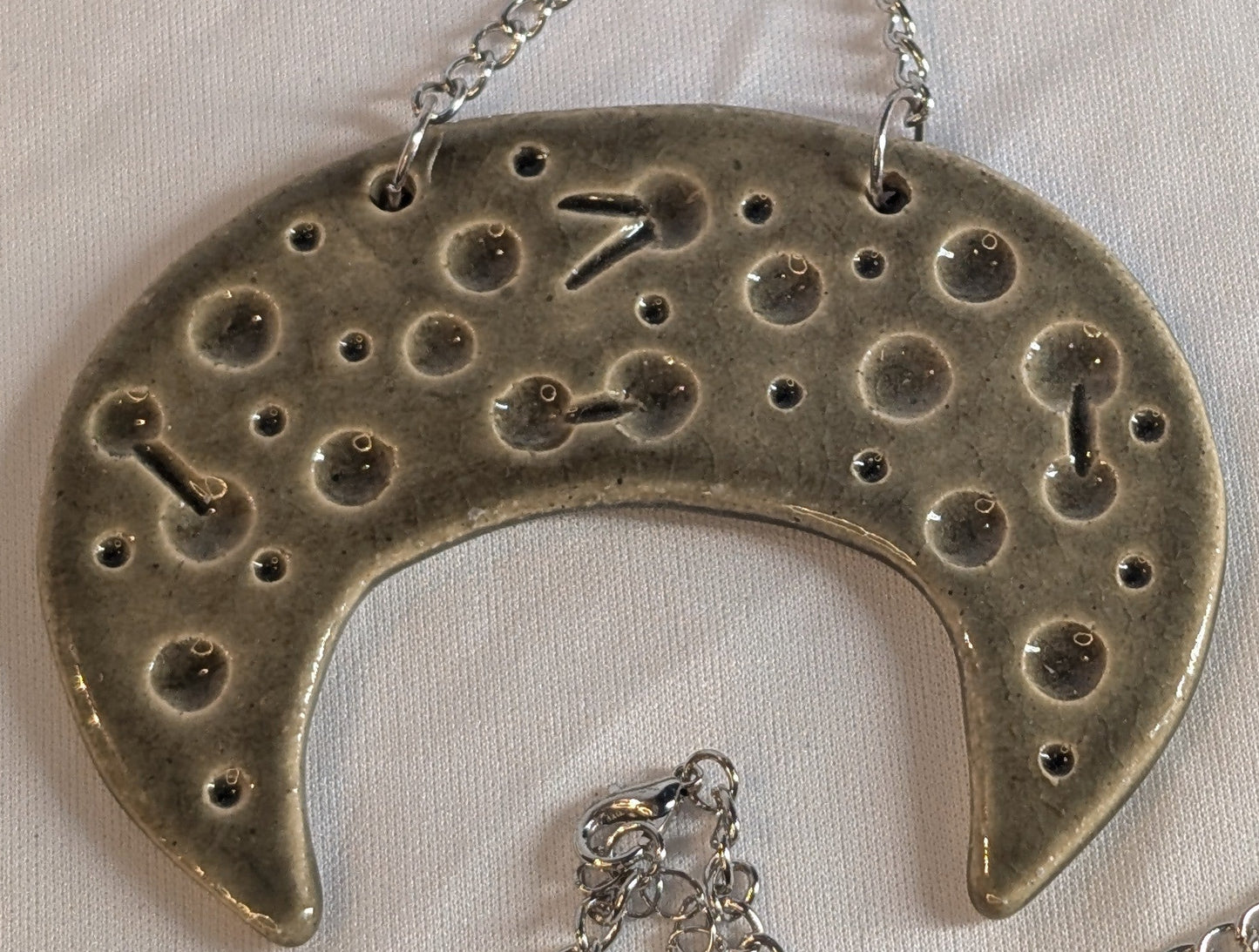 Silver necklace with a crescent moon pendant on a white background