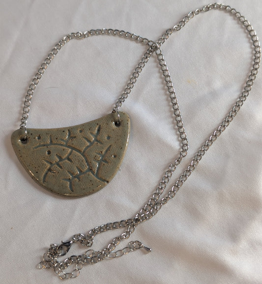 Silver necklace with a half-circle pendant on a light background