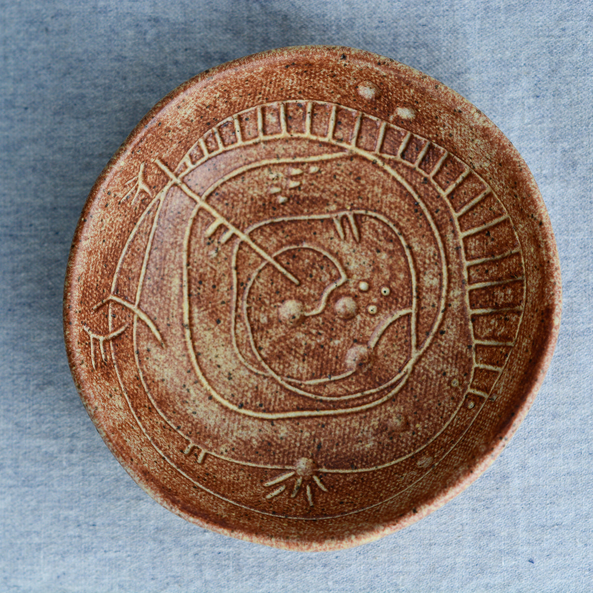 A handmade circular bowl with celestial and astrological carvings