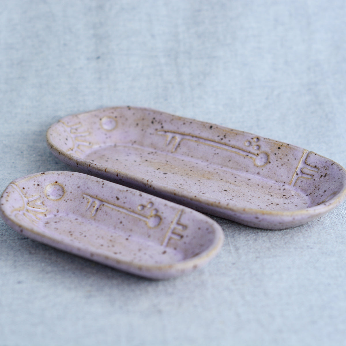 A charming set of small oblong dishes, perfect for holding rings, keys, or a splash of soy sauce. Each set is unique, featuring a distinctive hand-carved motif and a matching hand-painted finish.