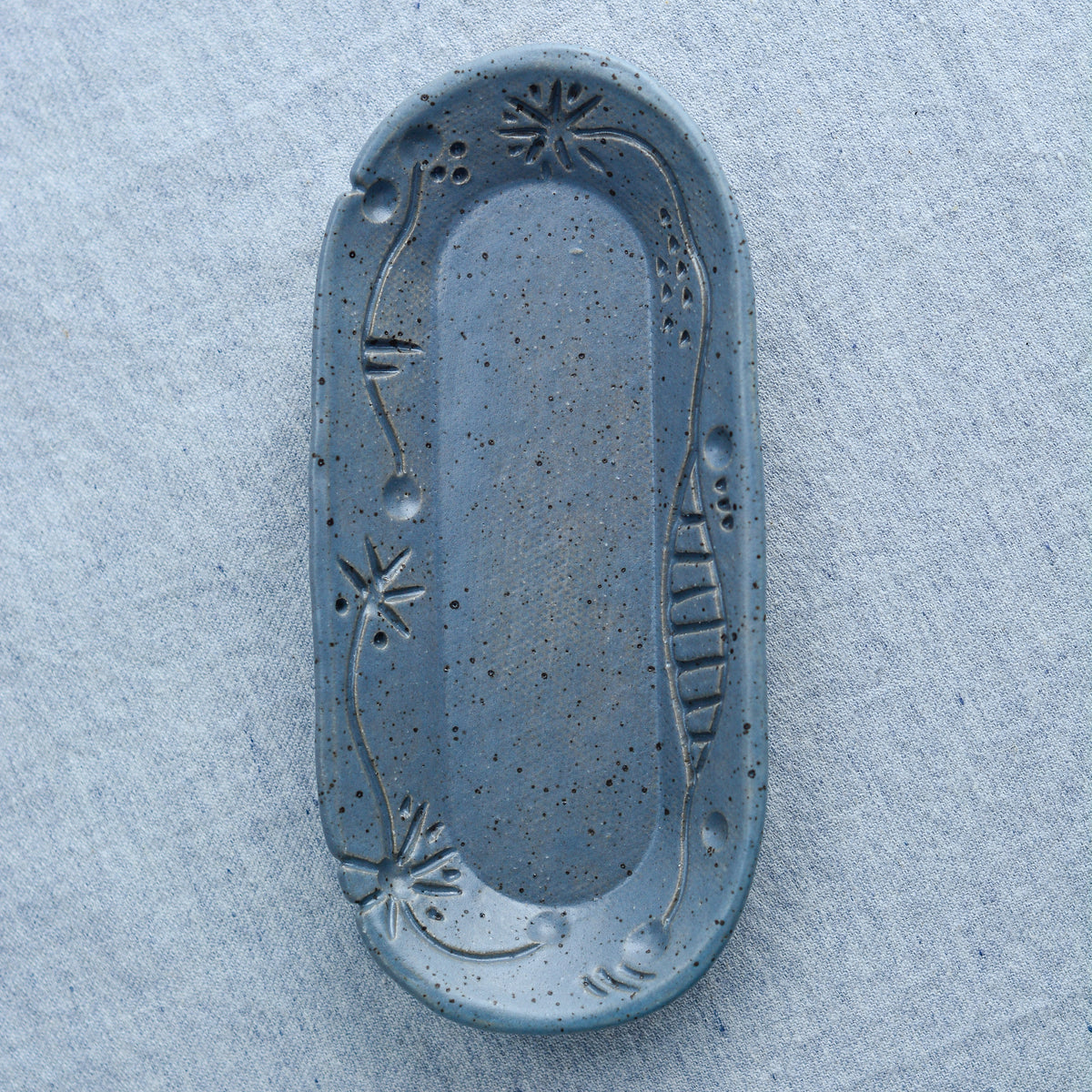 A charming oblong dish, ideal for holding rings, keys, or a splash of soy sauce. Each piece is unique, showcasing a distinctive hand-carved motif and a matching hand-painted finish.