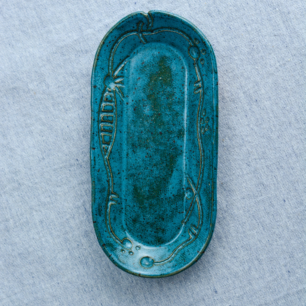 A charming oblong dish, ideal for holding rings, keys, or a splash of soy sauce. Each piece is unique, showcasing a distinctive hand-carved motif and a matching hand-painted finish.