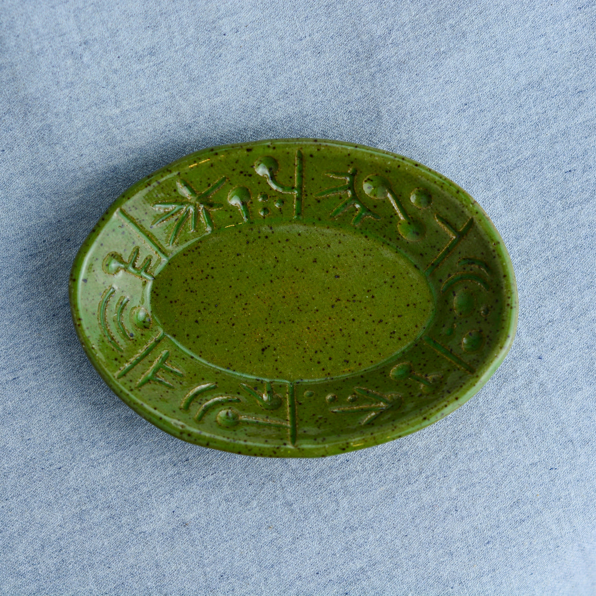 An oval shaped dish, ideal for holding rings, keys, or a splash of soy sauce. Each piece is unique, showcasing a distinctive hand-carved motif and a matching hand-painted finish.
