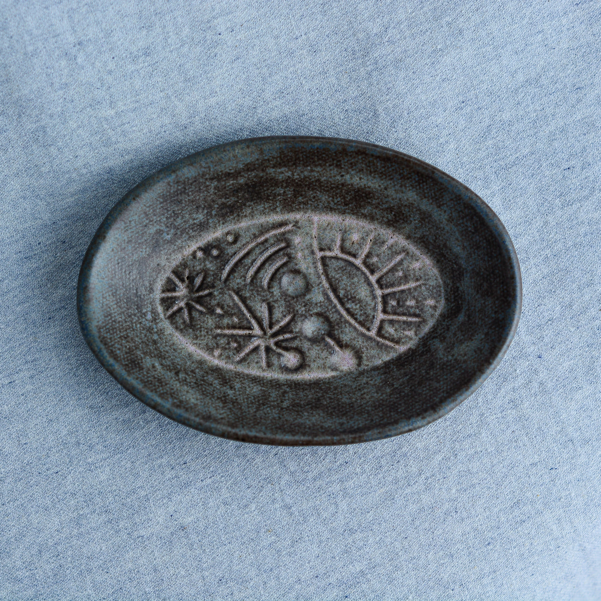 An oval shaped dish, ideal for holding rings, keys, or a splash of soy sauce. Each piece is unique, showcasing a distinctive hand-carved motif and a matching hand-painted finish.