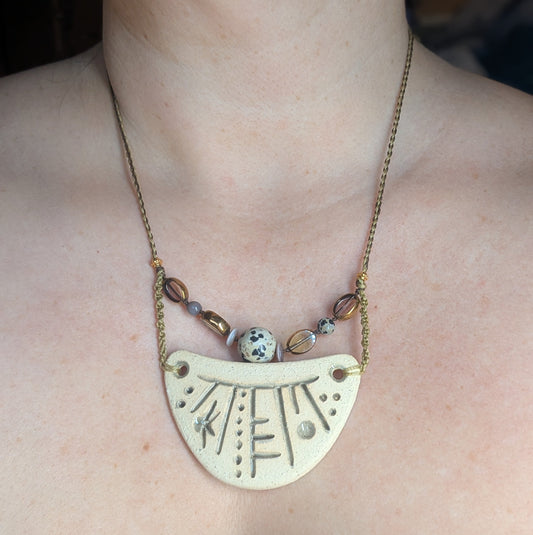 Necklace with a large, half-circle pendant worn by a person