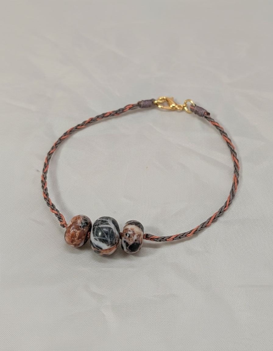 Bracelet with marbled beads and braided cord on a light gray background