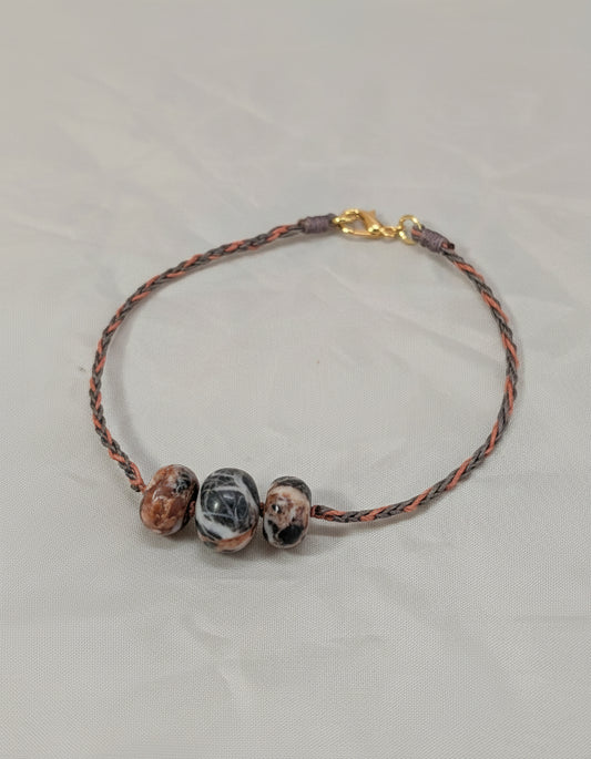 Bracelet with marbled beads and braided cord on a light gray background