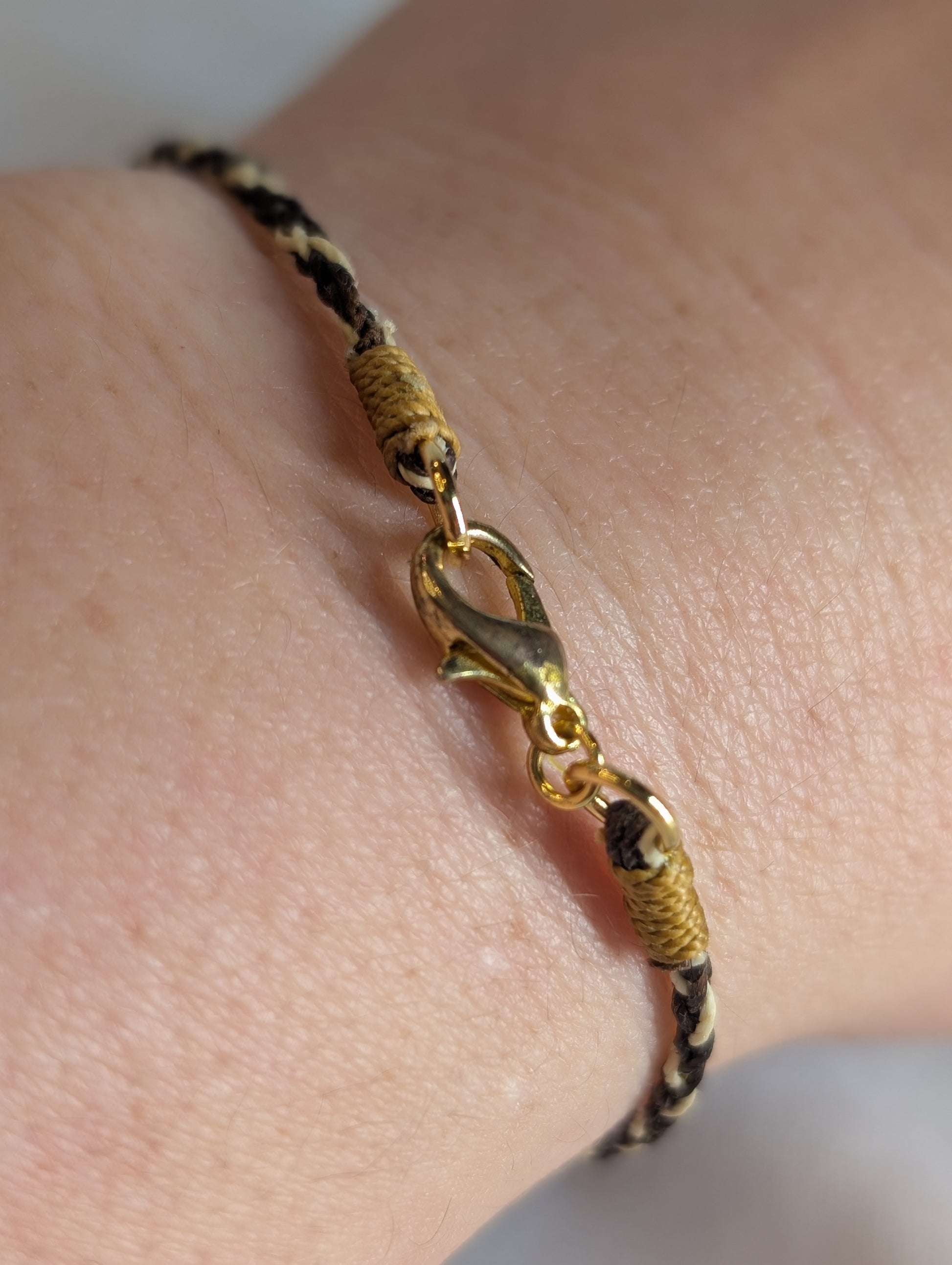 Gold bracelet with a unique design on a wrist against a neutral background