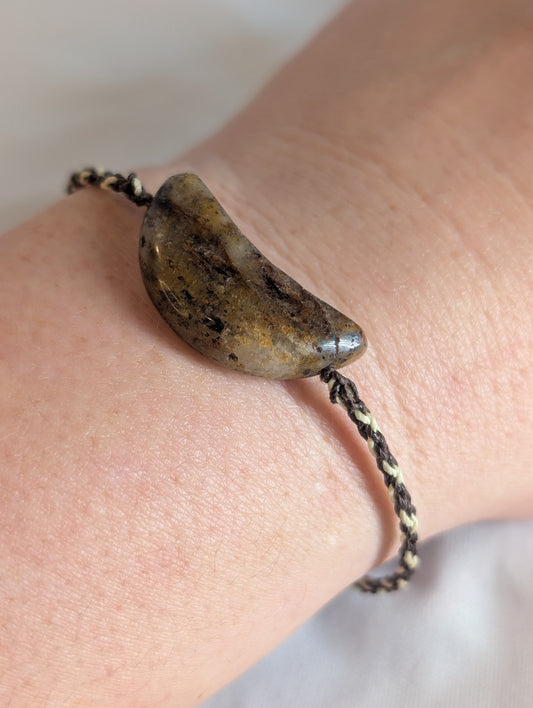 Bracelet with a large stone bead on a wrist against a neutral background