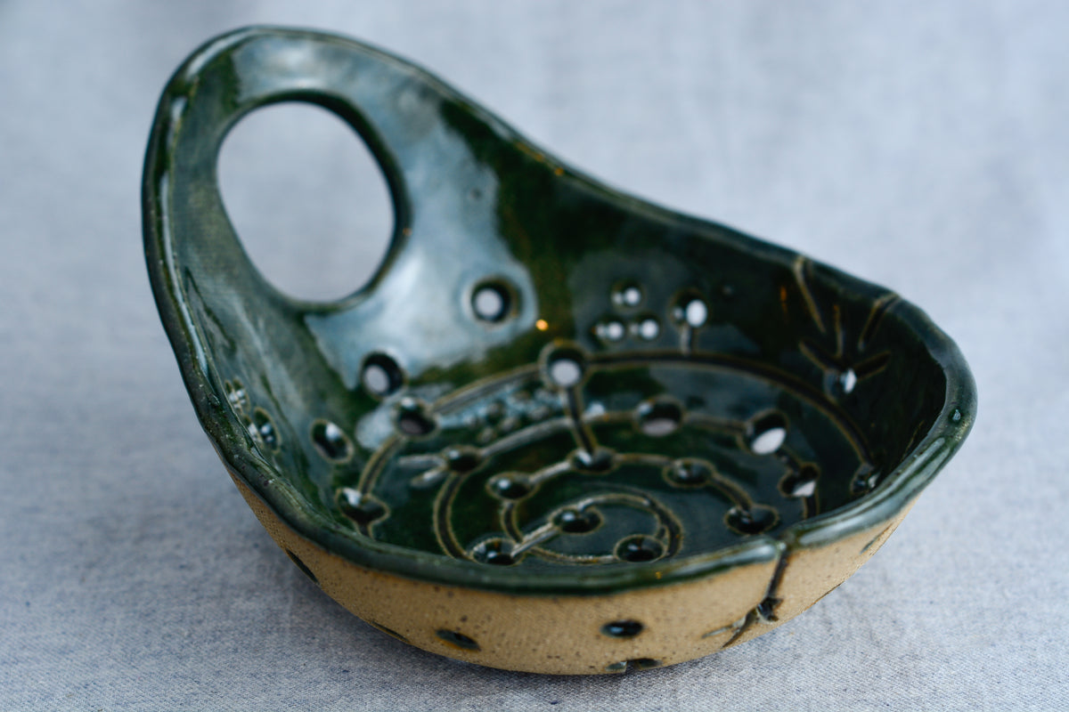 Handmade ceramic colander perfect for cleaning and storing bite-sized fruits.
