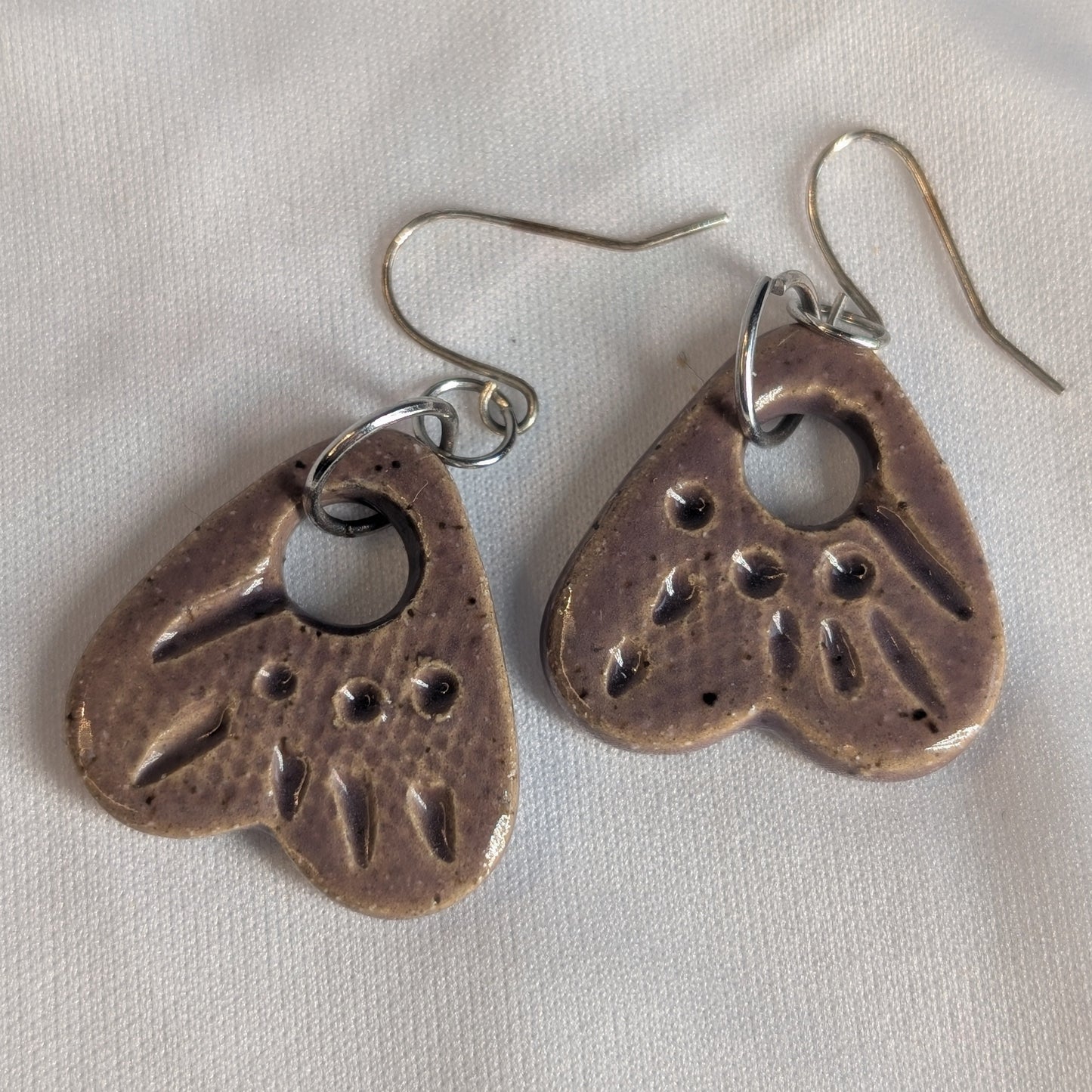Pair of ceramic heart-shaped earrings on a light gray background