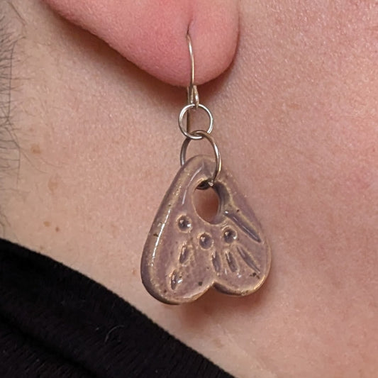 Close-up of a person wearing a silver earring with a heart design.