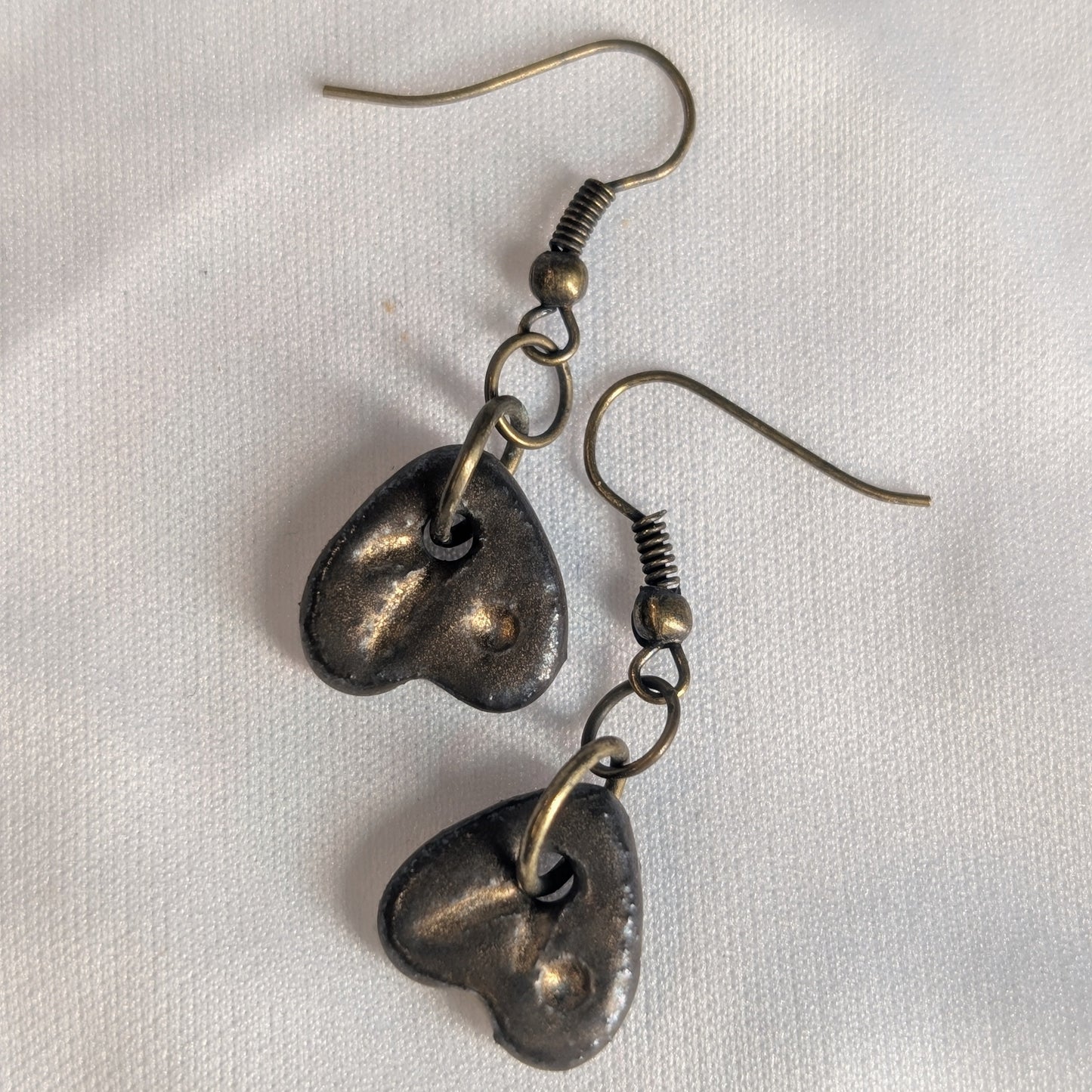 Pair of bronze ceramic heart-shaped earrings on a white background