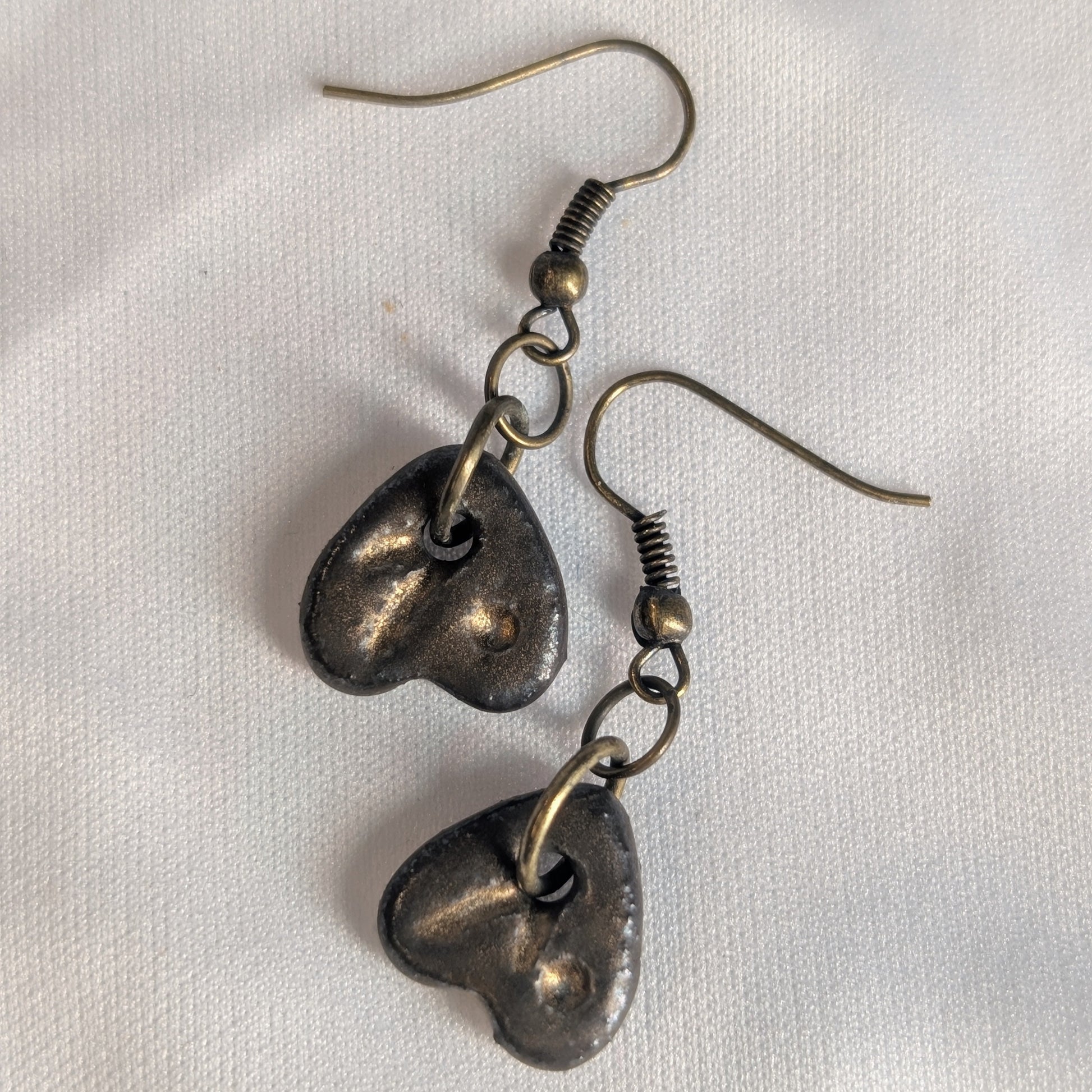 Pair of bronze ceramic heart-shaped earrings on a white background