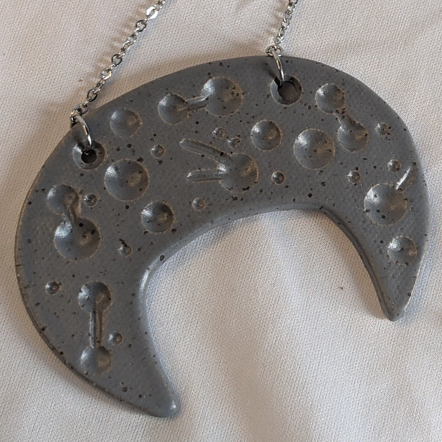 Metallic crescent-shaped pendant with chain on a white background, labeled '19"'.