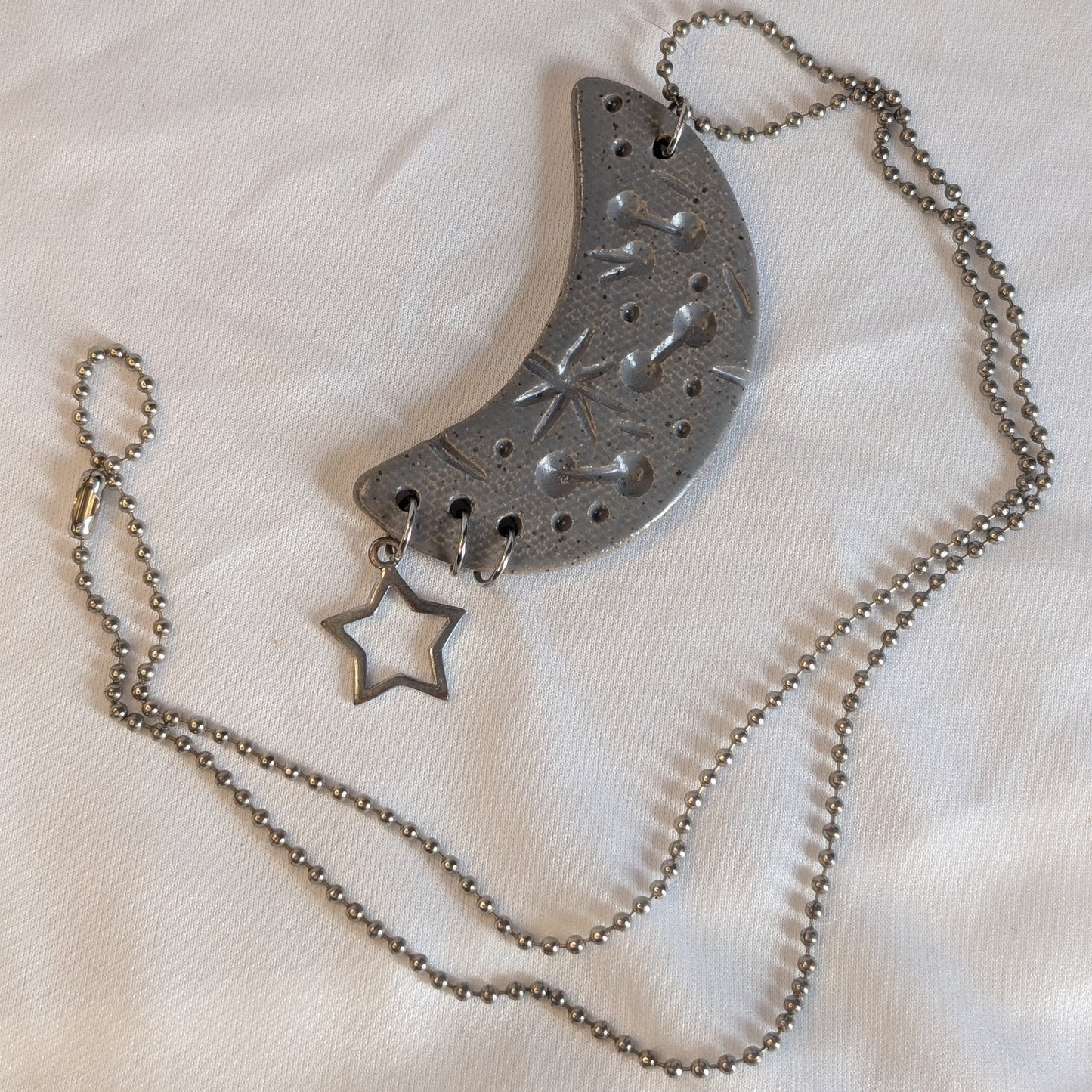 Silver necklace with a crescent moon and star pendant on a white background