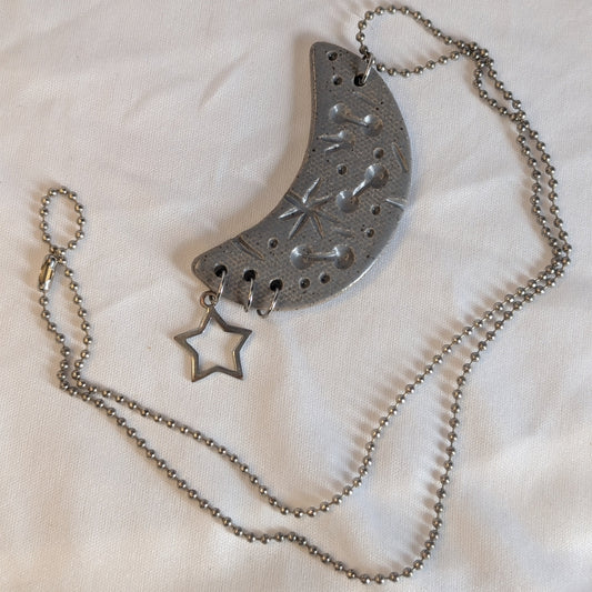 Silver necklace with a crescent moon and star pendant on a white background