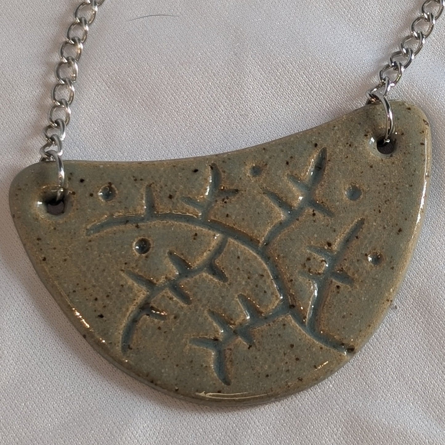 Silver necklace with a half-circle pendant on a white background