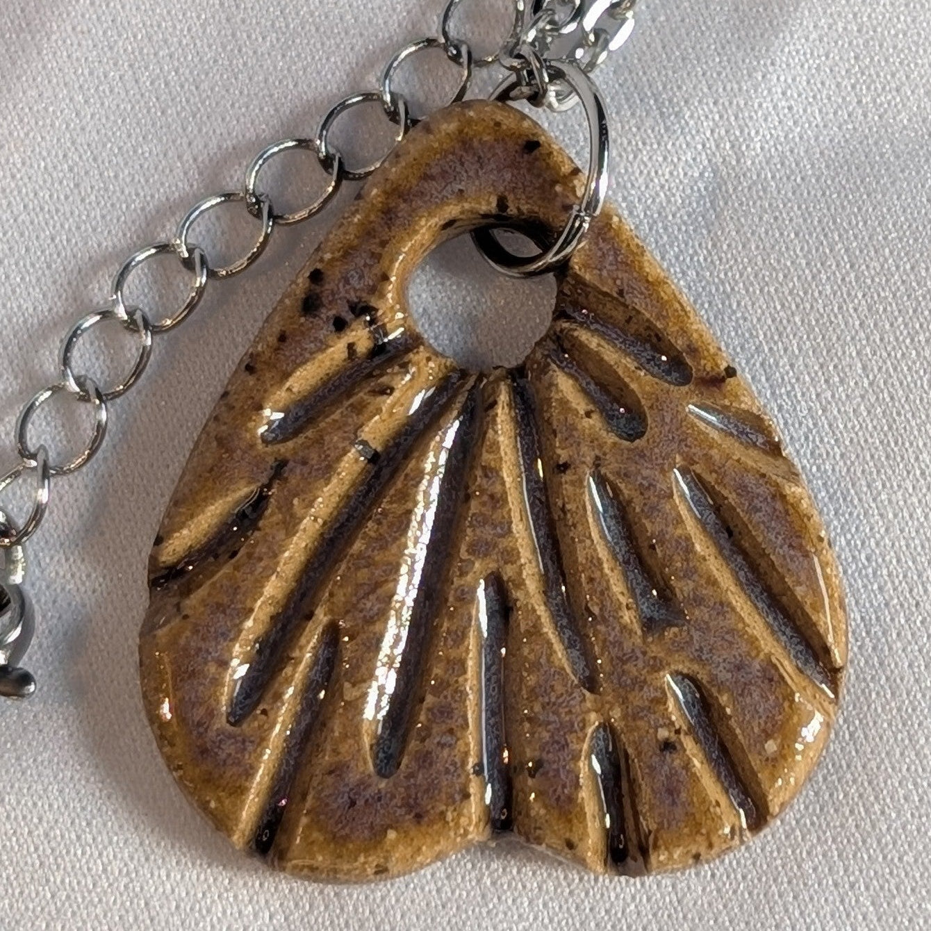 Necklace with a carved ceramic pendant on a white background