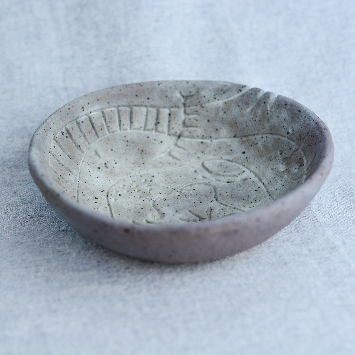 A handmade circular bowl with celestial and astrological carvings