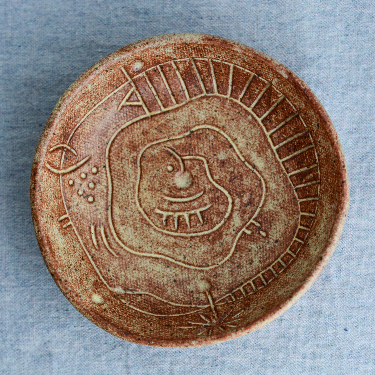 A handmade circular bowl with celestial and astrological carvings