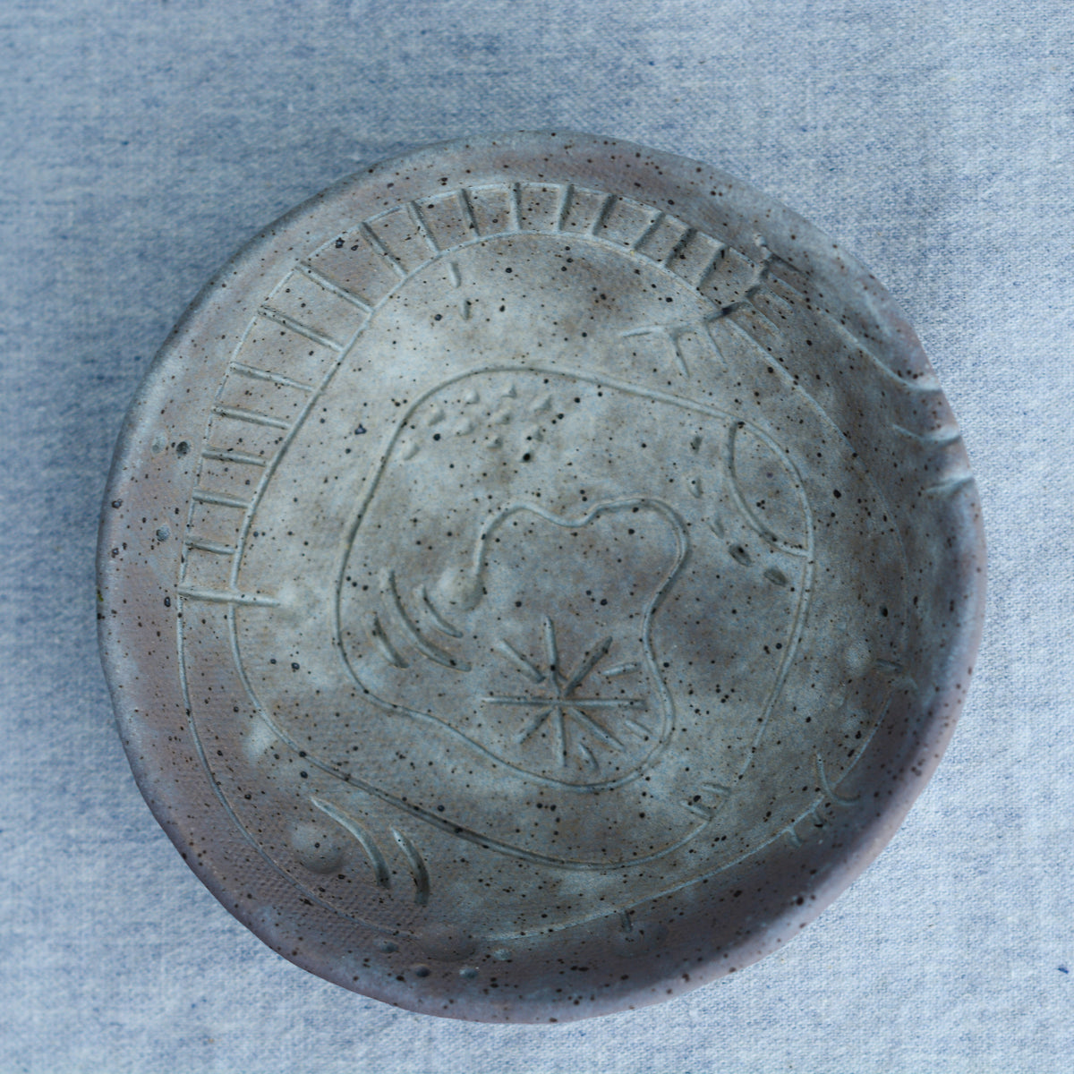 A handmade circular bowl with celestial and astrological carvings