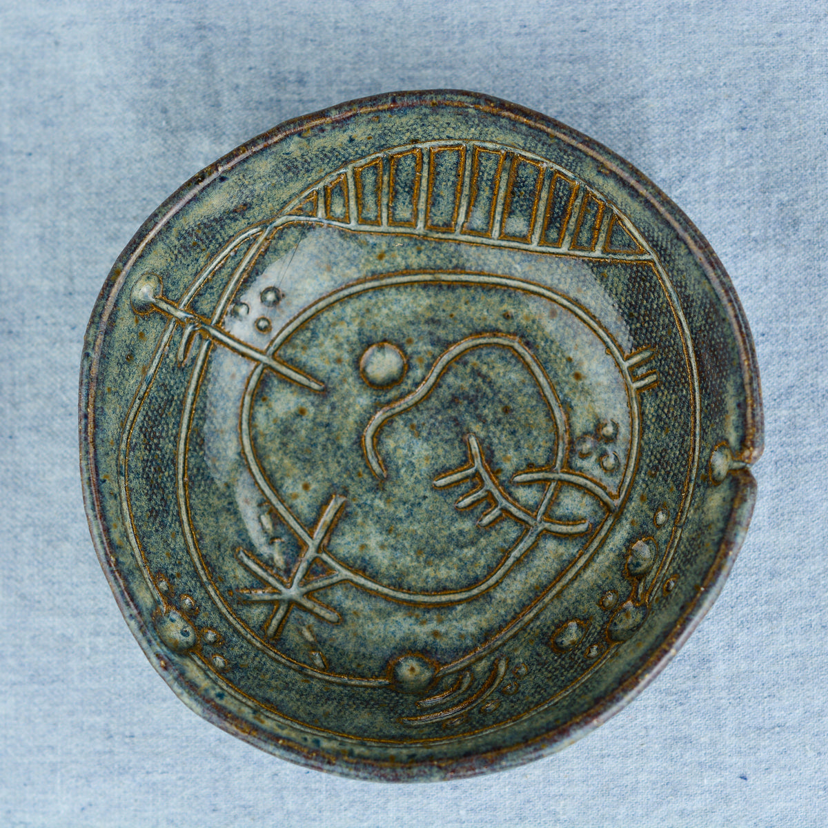 A handmade circular bowl with celestial and astrological carvings