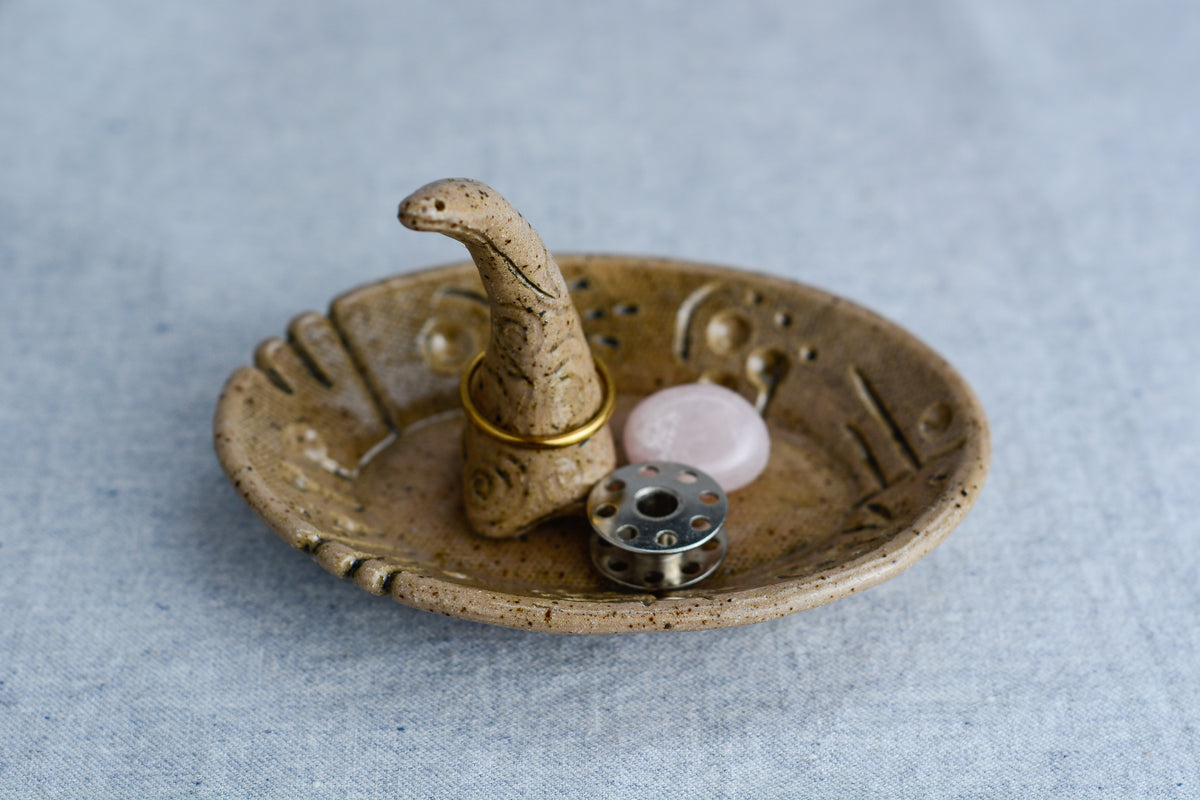 Ceramic ring tray featuring a tiny dinoasur-like creature; created with a mix of sculpture, slab work, and surface design