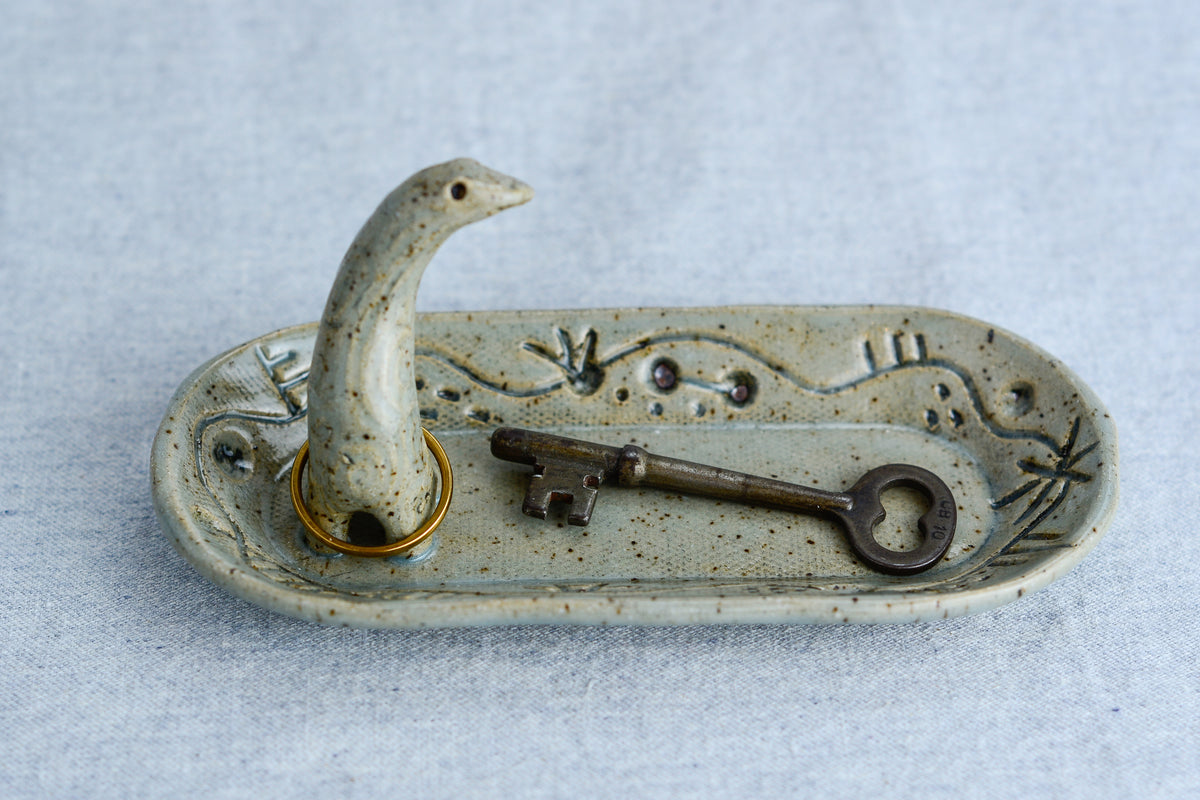 Ceramic ring tray featuring a tiny dinoasur-like creature; created with a mix of sculpture, slab work, and surface design