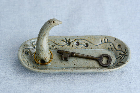Ceramic ring tray featuring a tiny dinoasur-like creature; created with a mix of sculpture, slab work, and surface design