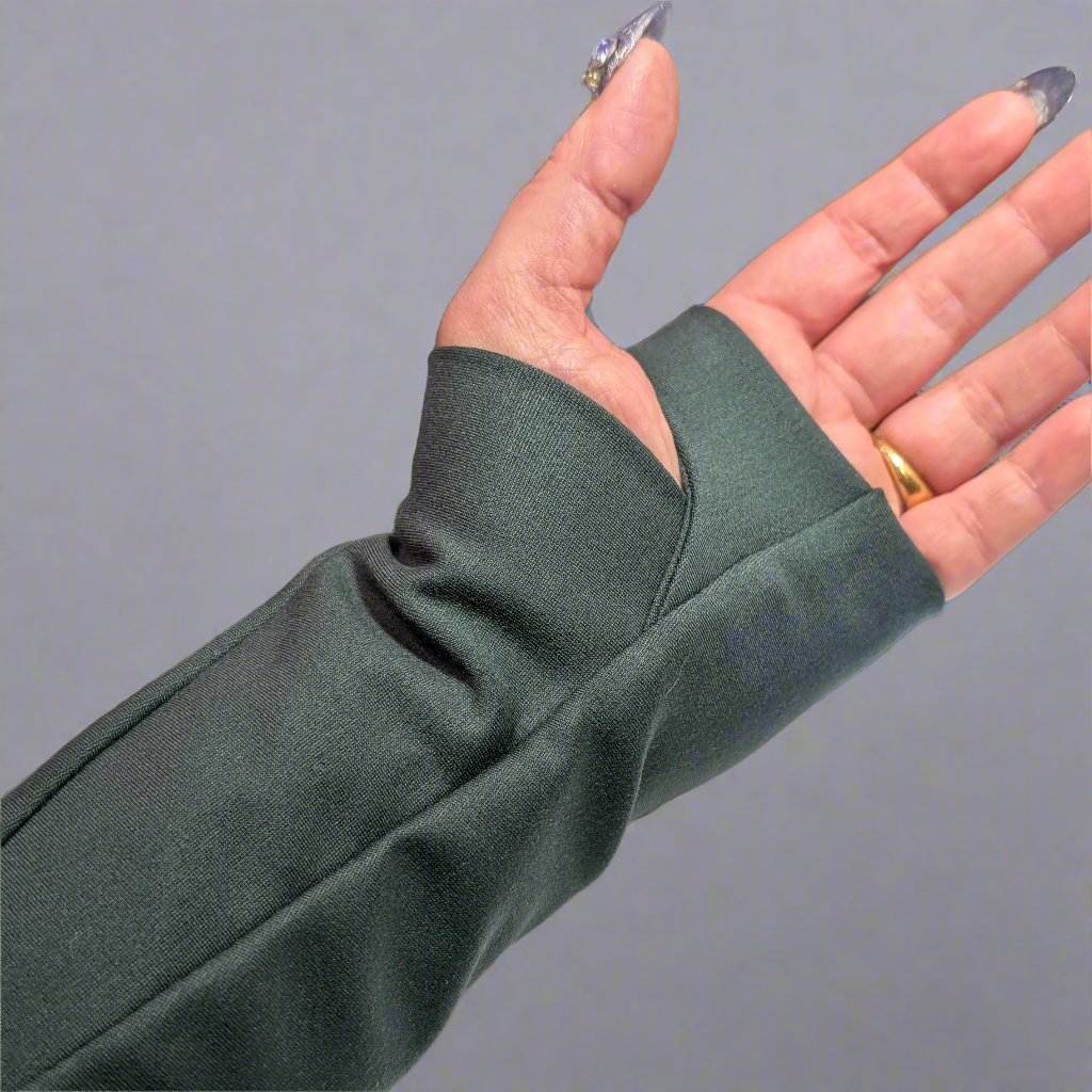 A hand and wrist showing detail of the thumbhole in a long sleeve coat