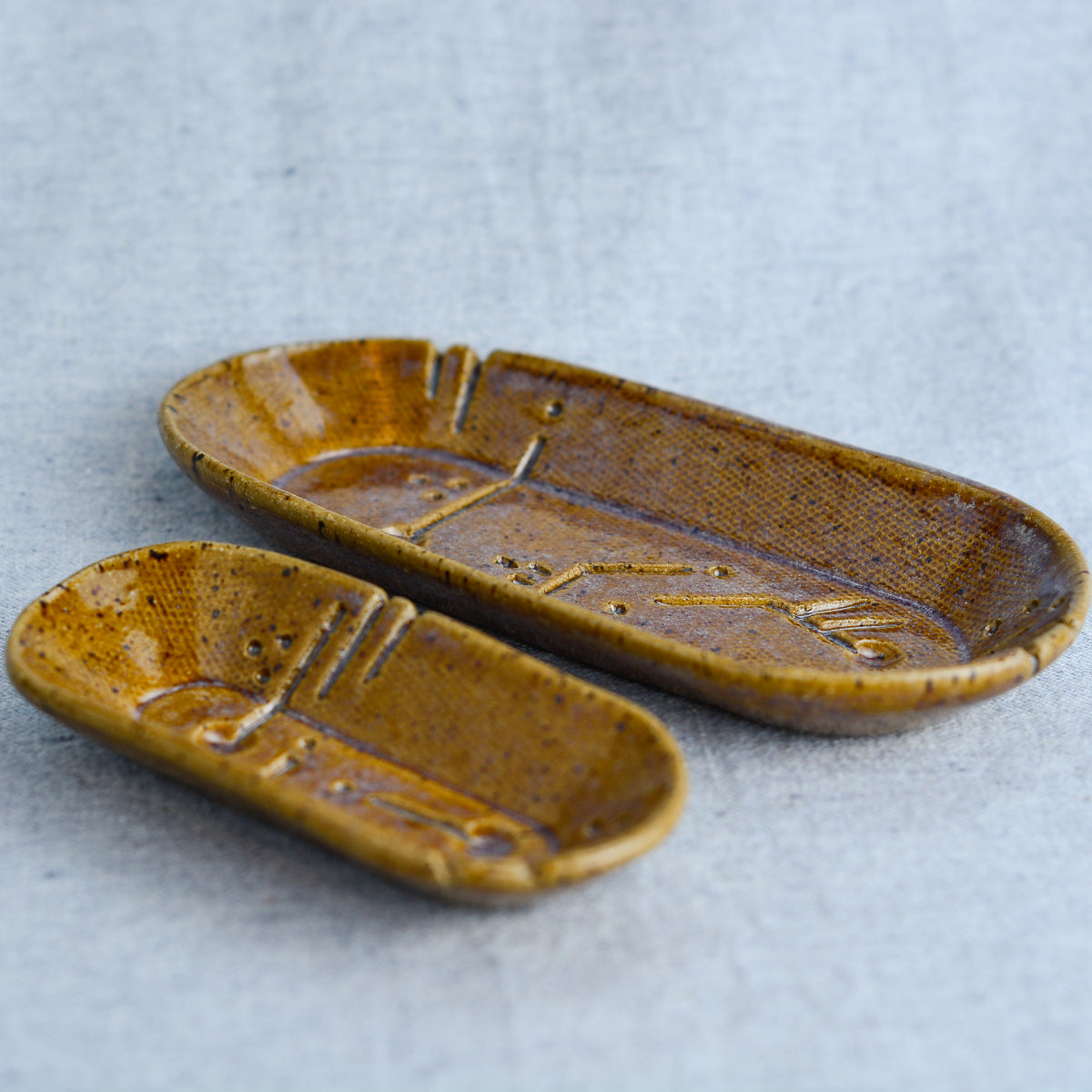 A charming set of small oblong dishes, perfect for holding rings, keys, or a splash of soy sauce. Each set is unique, featuring a distinctive hand-carved motif and a matching hand-painted finish.