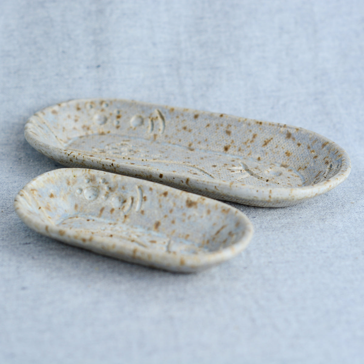 A charming set of small oblong dishes, perfect for holding rings, keys, or a splash of soy sauce. Each set is unique, featuring a distinctive hand-carved motif and a matching hand-painted finish.