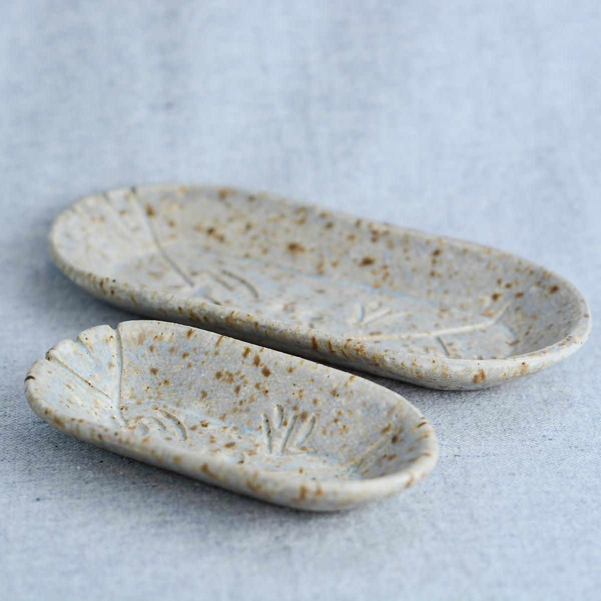 A charming set of small oblong dishes, perfect for holding rings, keys, or a splash of soy sauce. Each set is unique, featuring a distinctive hand-carved motif and a matching hand-painted finish.