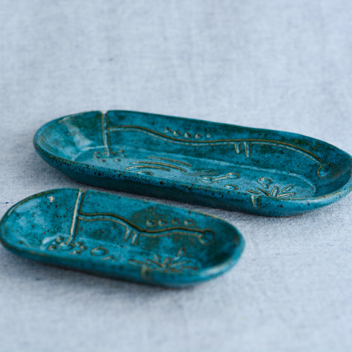 A charming set of small oblong dishes, perfect for holding rings, keys, or a splash of soy sauce. Each set is unique, featuring a distinctive hand-carved motif and a matching hand-painted finish.