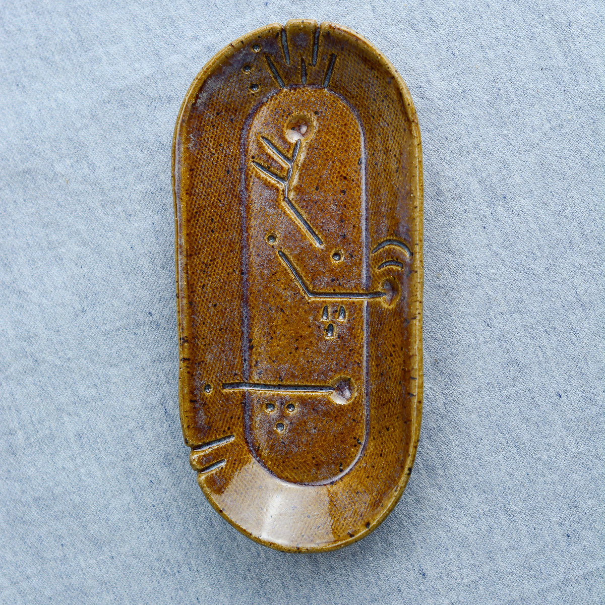 A charming oblong dish, ideal for holding rings, keys, or a splash of soy sauce. Each piece is unique, showcasing a distinctive hand-carved motif and a matching hand-painted finish.