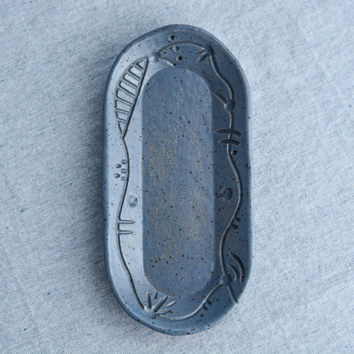 A charming oblong dish, ideal for holding rings, keys, or a splash of soy sauce. Each piece is unique, showcasing a distinctive hand-carved motif and a matching hand-painted finish.