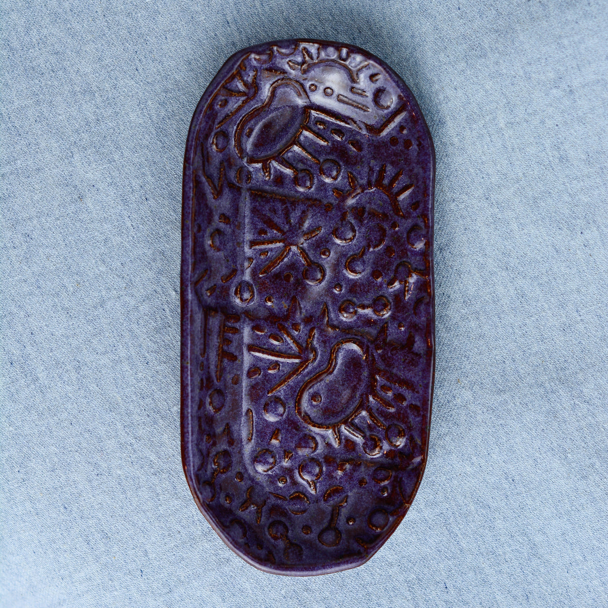 A charming oblong dish, ideal for holding rings, keys, or a splash of soy sauce. Each piece is unique, showcasing a distinctive hand-carved motif and a matching hand-painted finish.