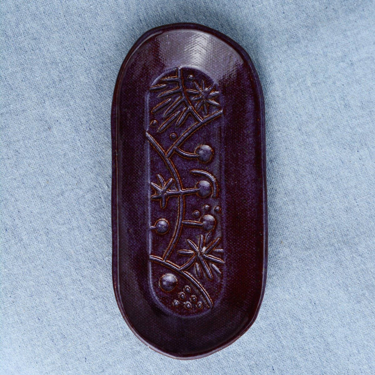 A charming oblong dish, ideal for holding rings, keys, or a splash of soy sauce. Each piece is unique, showcasing a distinctive hand-carved motif and a matching hand-painted finish.