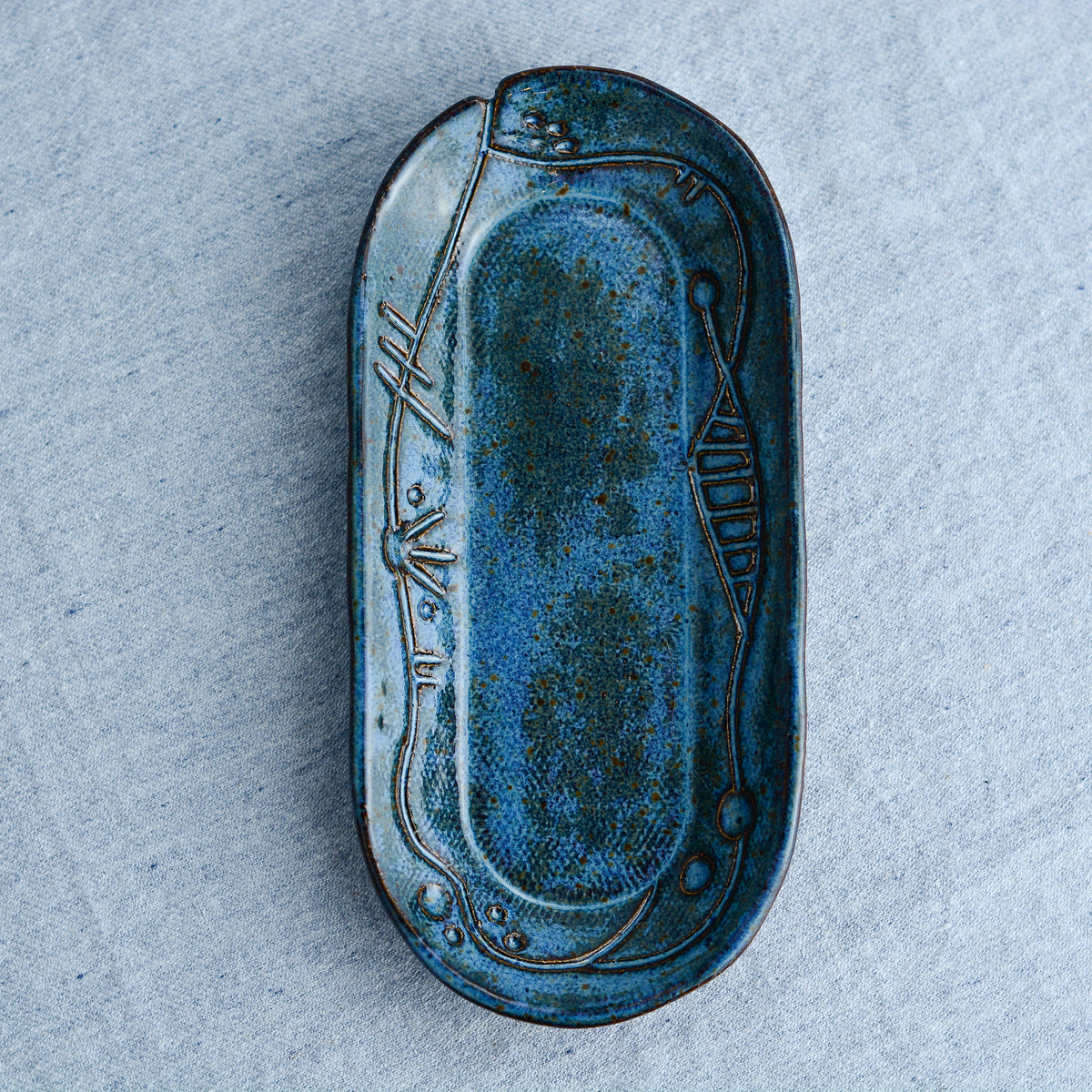 A charming oblong dish, ideal for holding rings, keys, or a splash of soy sauce. Each piece is unique, showcasing a distinctive hand-carved motif and a matching hand-painted finish.