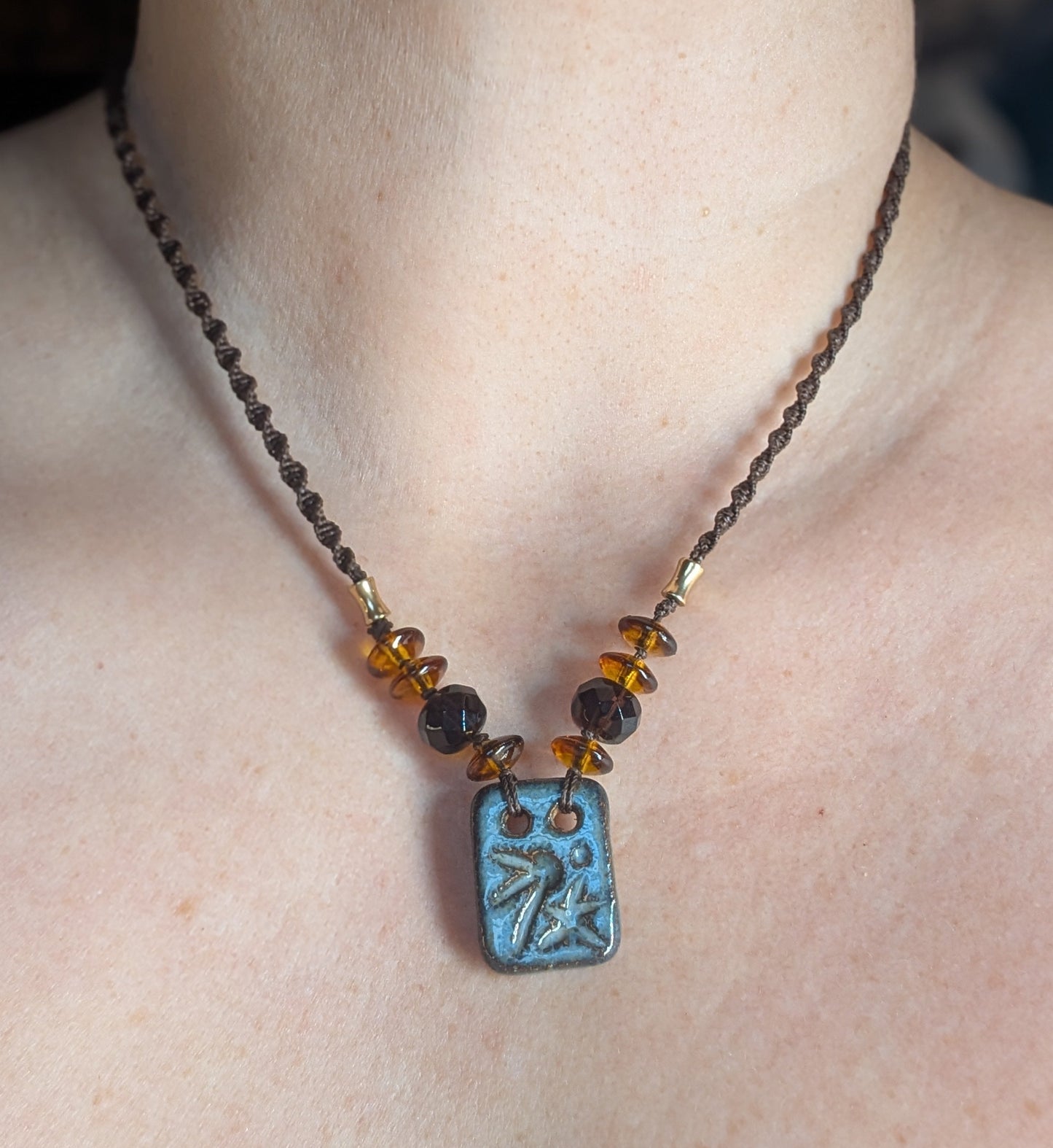 Necklace with a blue pendant on a person's neck