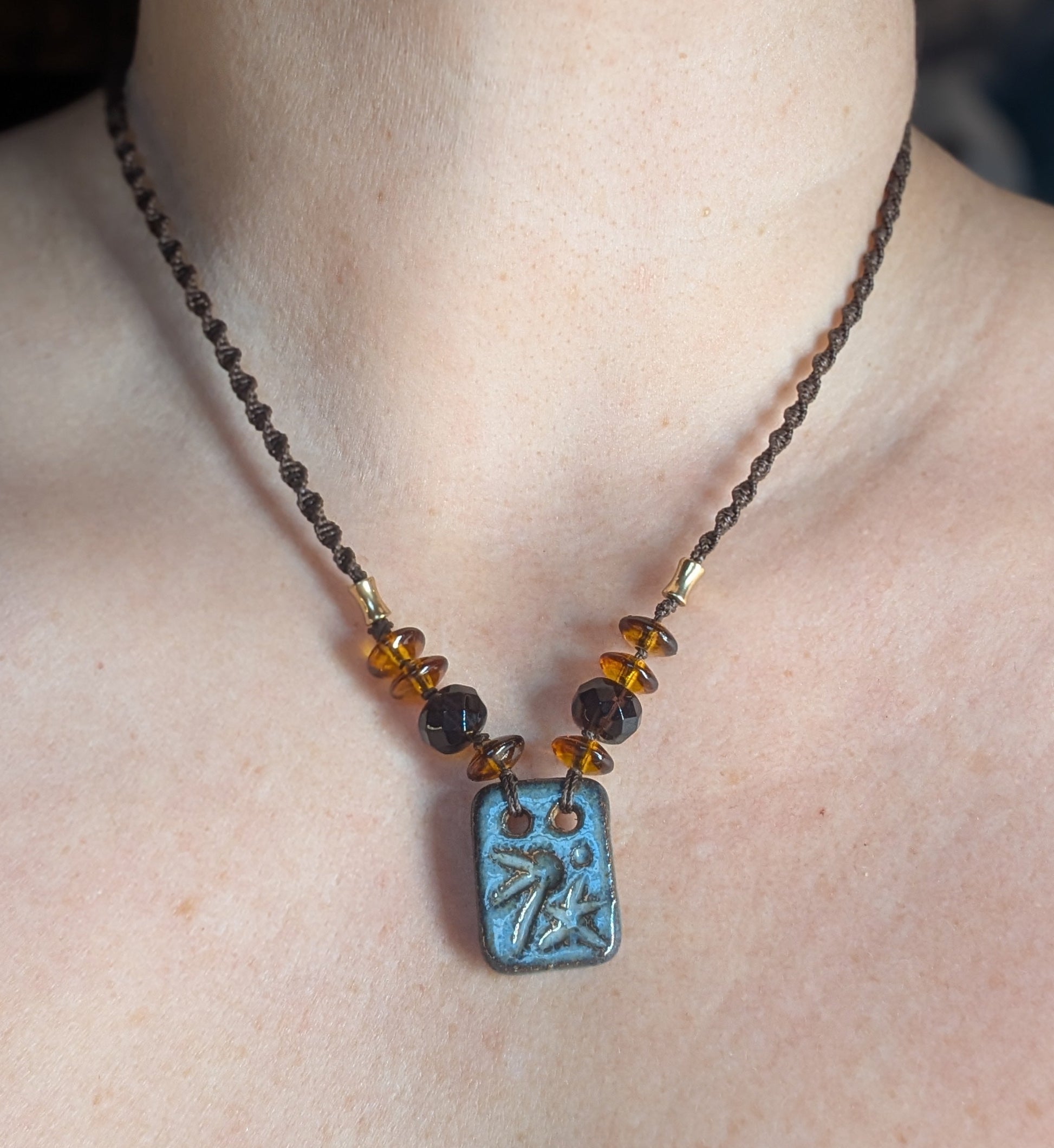 Necklace with a blue pendant on a person's neck