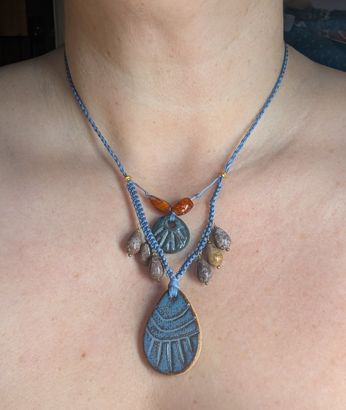 Necklace with blue cord and various pendants on a person's neck