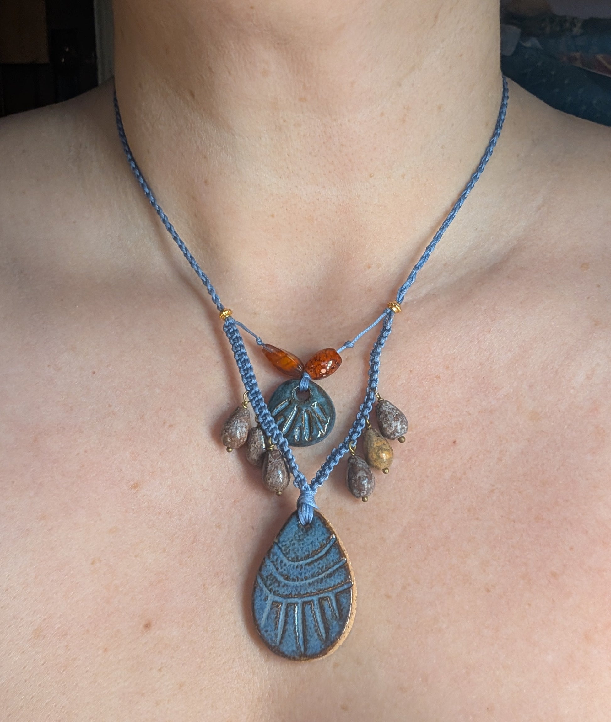 Necklace with blue cord and various pendants on a person's neck