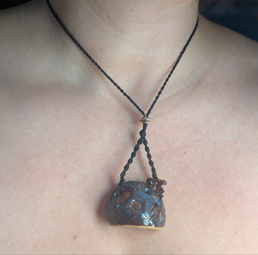 Necklace with a decorative pendant on a person's neck against a neutral background