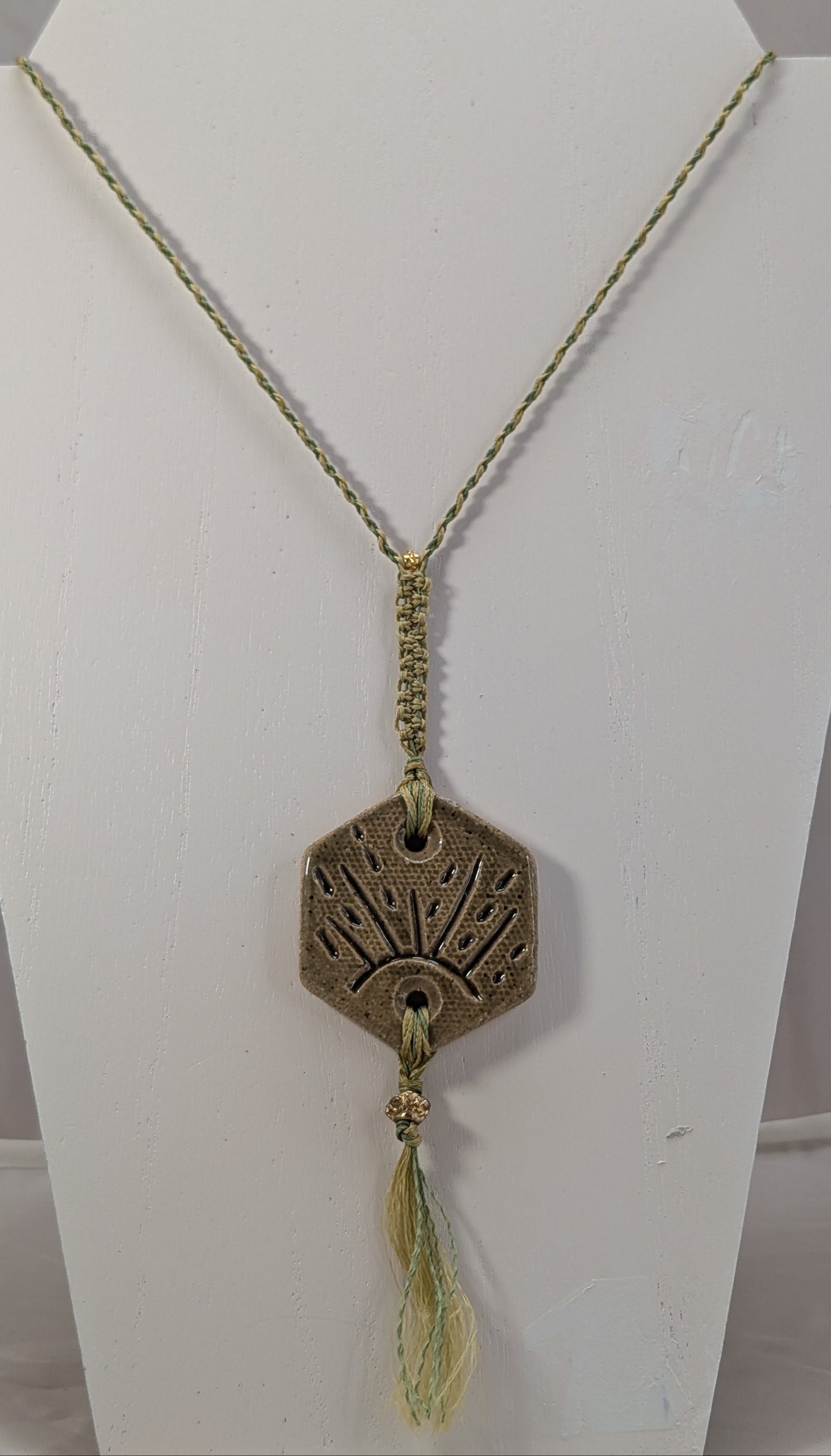 Necklace with a decorative pendant on a white stand