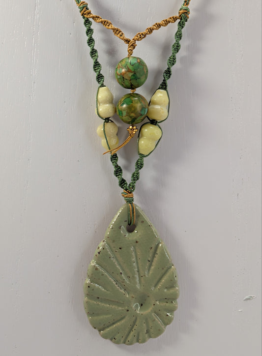Necklace with green beads and a leaf-shaped pendant on a white background
