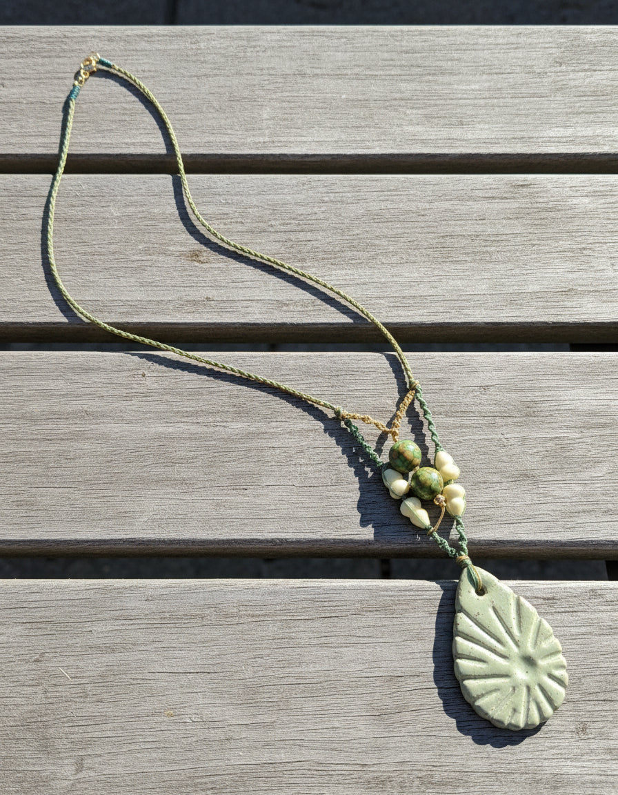 Necklace with a green pendant on a textured surface